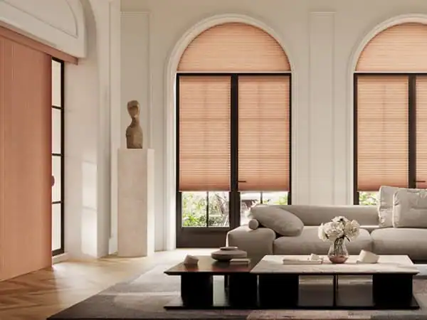Modern living room with arched windows covered by beige blinds, a gray sofa, a coffee table, and minimalist décor.